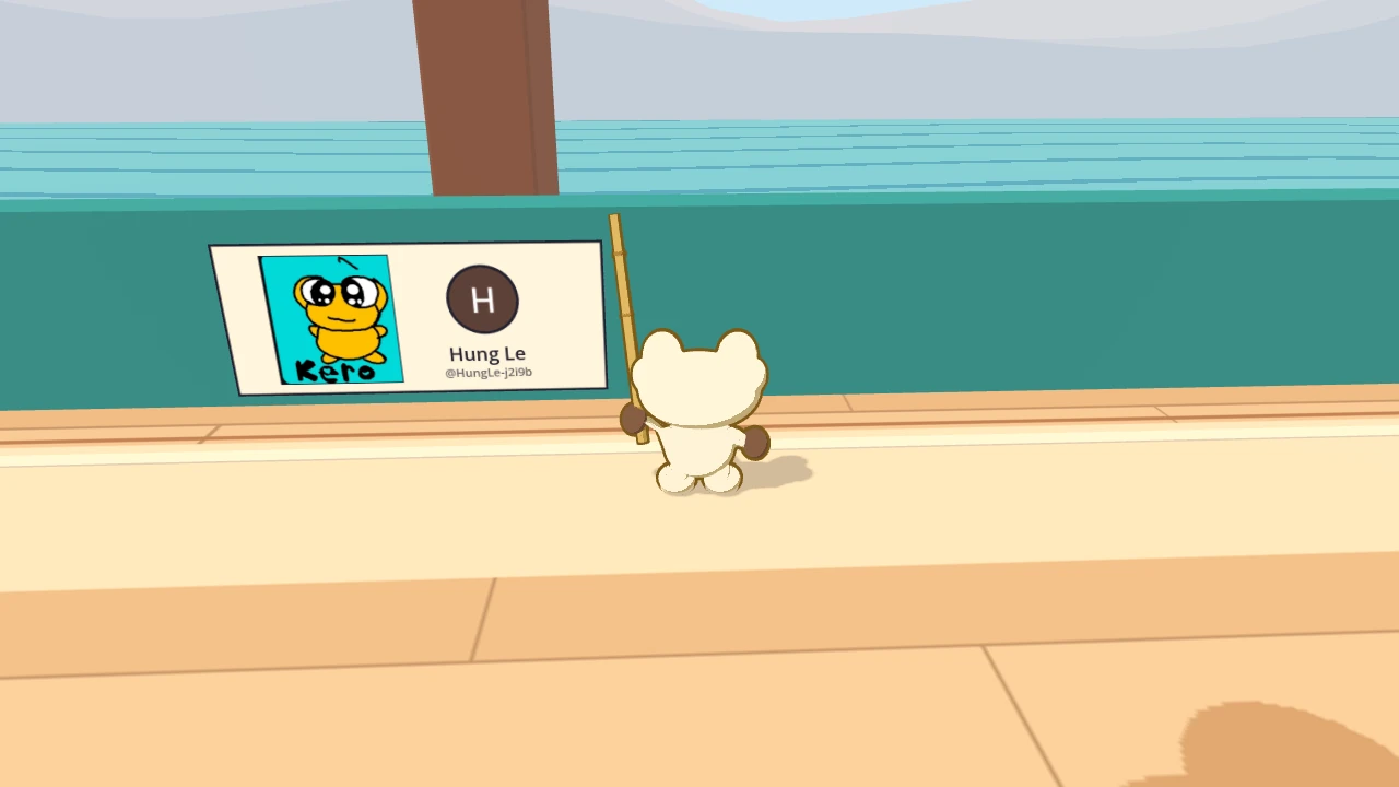 Hung Le’s panel on the seawall, with the sea behind it. It holds a yellow Kero on a turquoise background, and beside it a round picture with the letter H, the name Hung Le and @HungLe-j2i9b. Kero stands next to it.